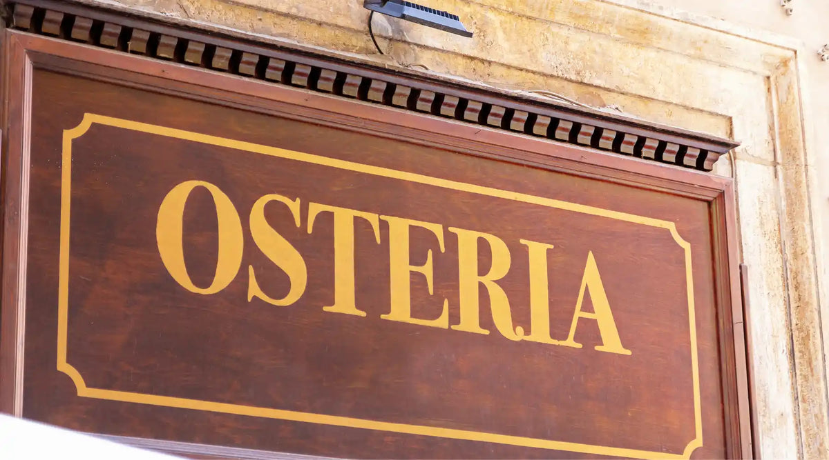 Panneau en bois traditionnel avec l’inscription « OSTERIA », typique des auberges italiennes authentiques.