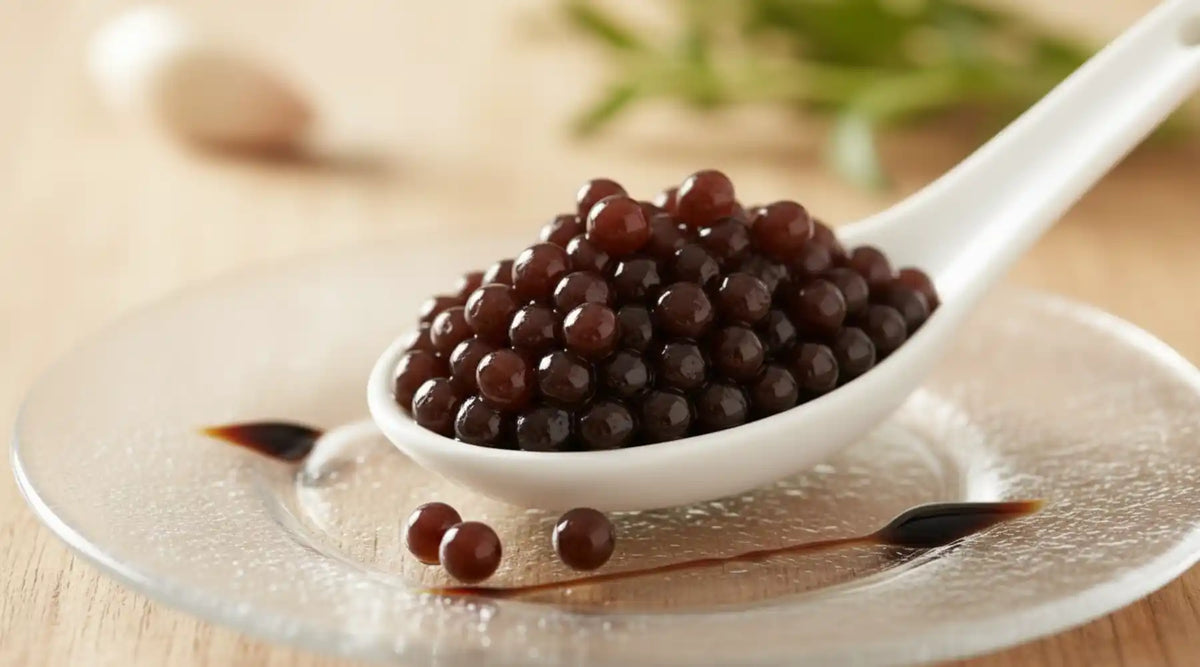 Perles de vinaigre balsamique dans une cuillère blanche sur assiette transparente
